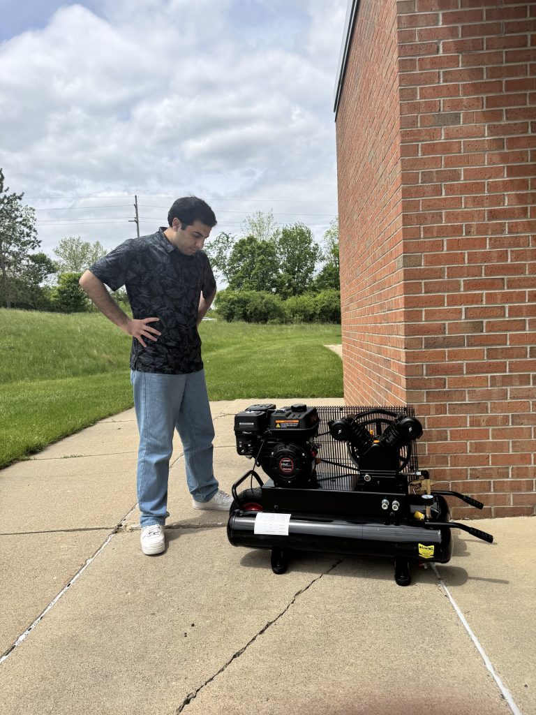 A graduate researcher inspecting a portable air compressor during a field test